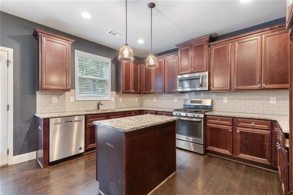 1023 Ruddy Duck Drive Jefferson, GA 30549 - Photo 19 of 69 a kitchen with stainless steel appliances granite countertop wooden cabinets a sink a stove a refrigerator and island with wooden floor