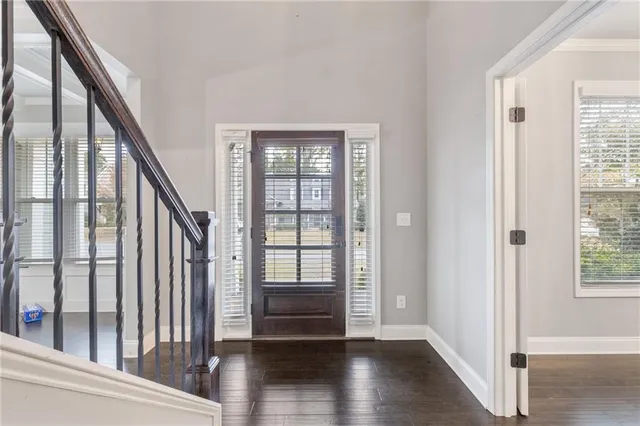 a view of an empty room with chandelier fan and wooden floor