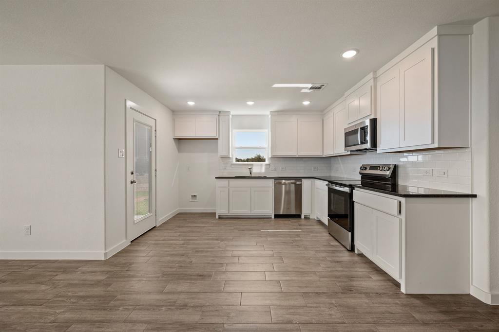 1016 Gatlin Circle Springtown, TX 76082 - Photo 12 of 30 a kitchen with granite countertop a stove top oven and cabinets