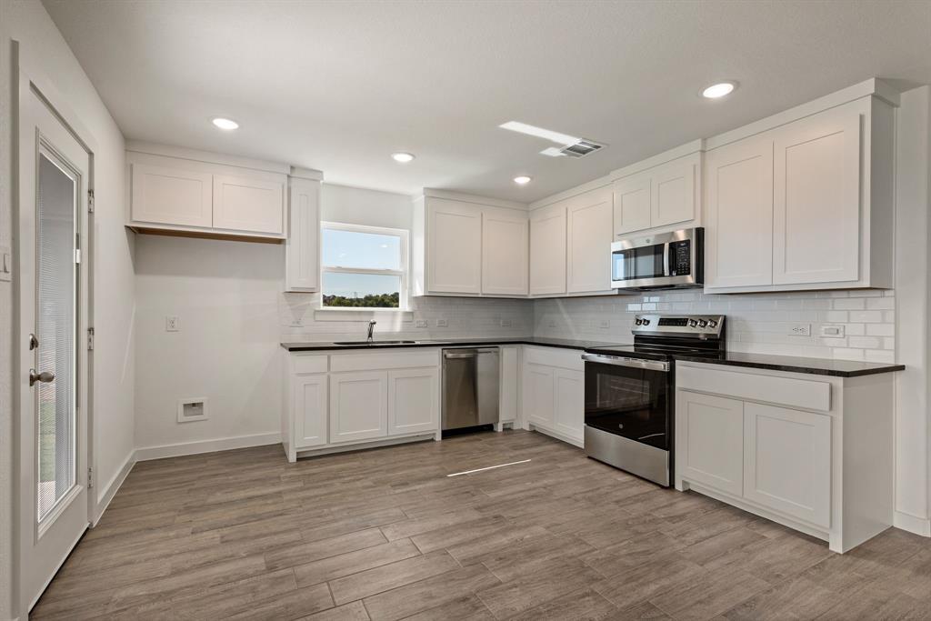 1016 Gatlin Circle Springtown, TX 76082 - Photo 13 of 30 a kitchen with granite countertop white cabinets and stainless steel appliances