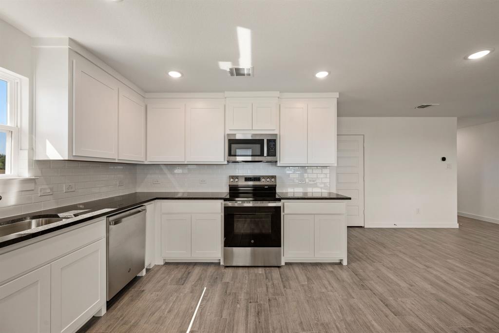 1016 Gatlin Circle Springtown, TX 76082 - Photo 17 of 30 a kitchen with granite countertop a stove top oven and cabinets