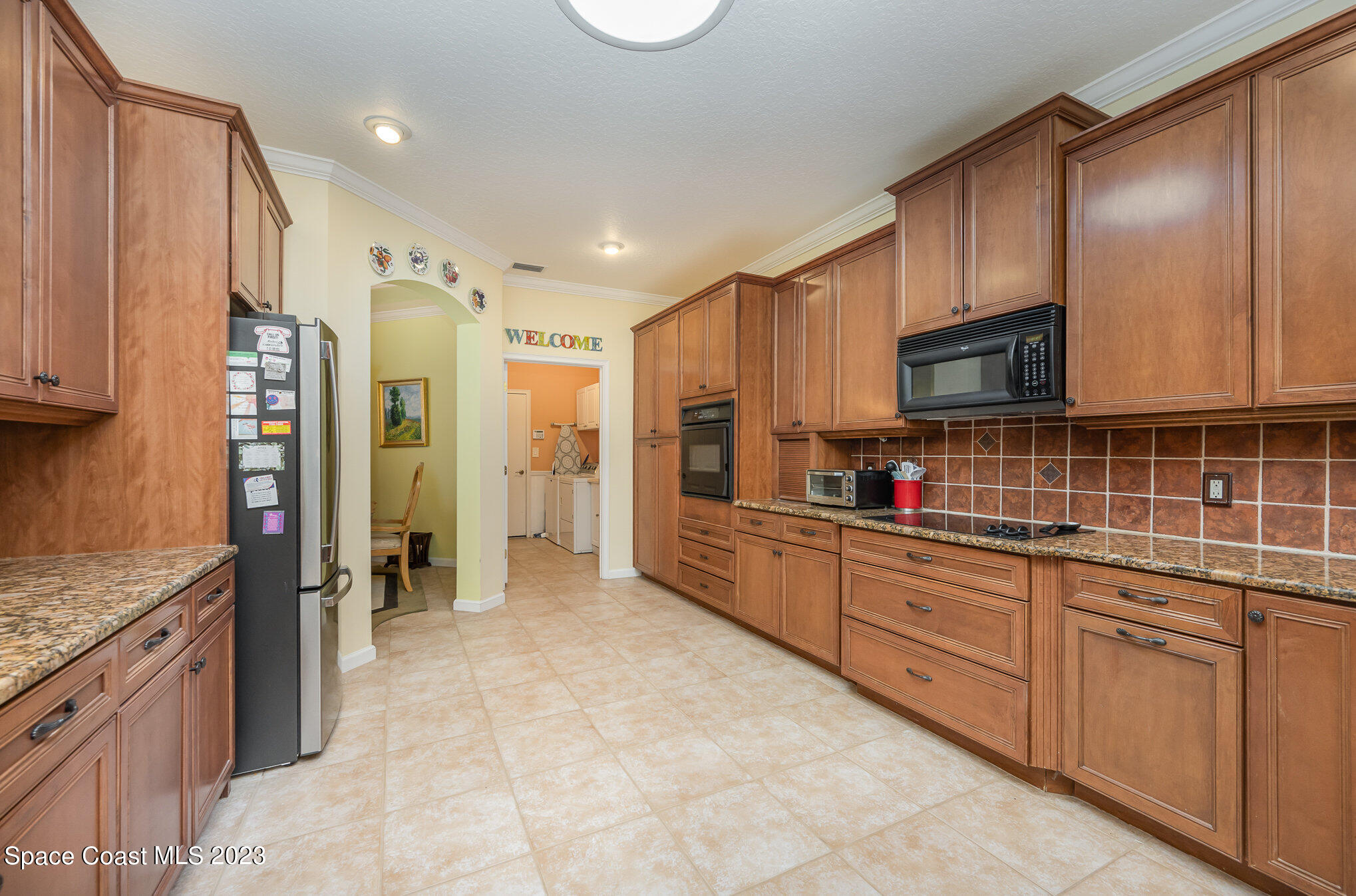 6972 Premonition Drive Melbourne, FL 32940 - Photo 12 of 33 a kitchen with stainless steel appliances granite countertop a refrigerator and cabinets