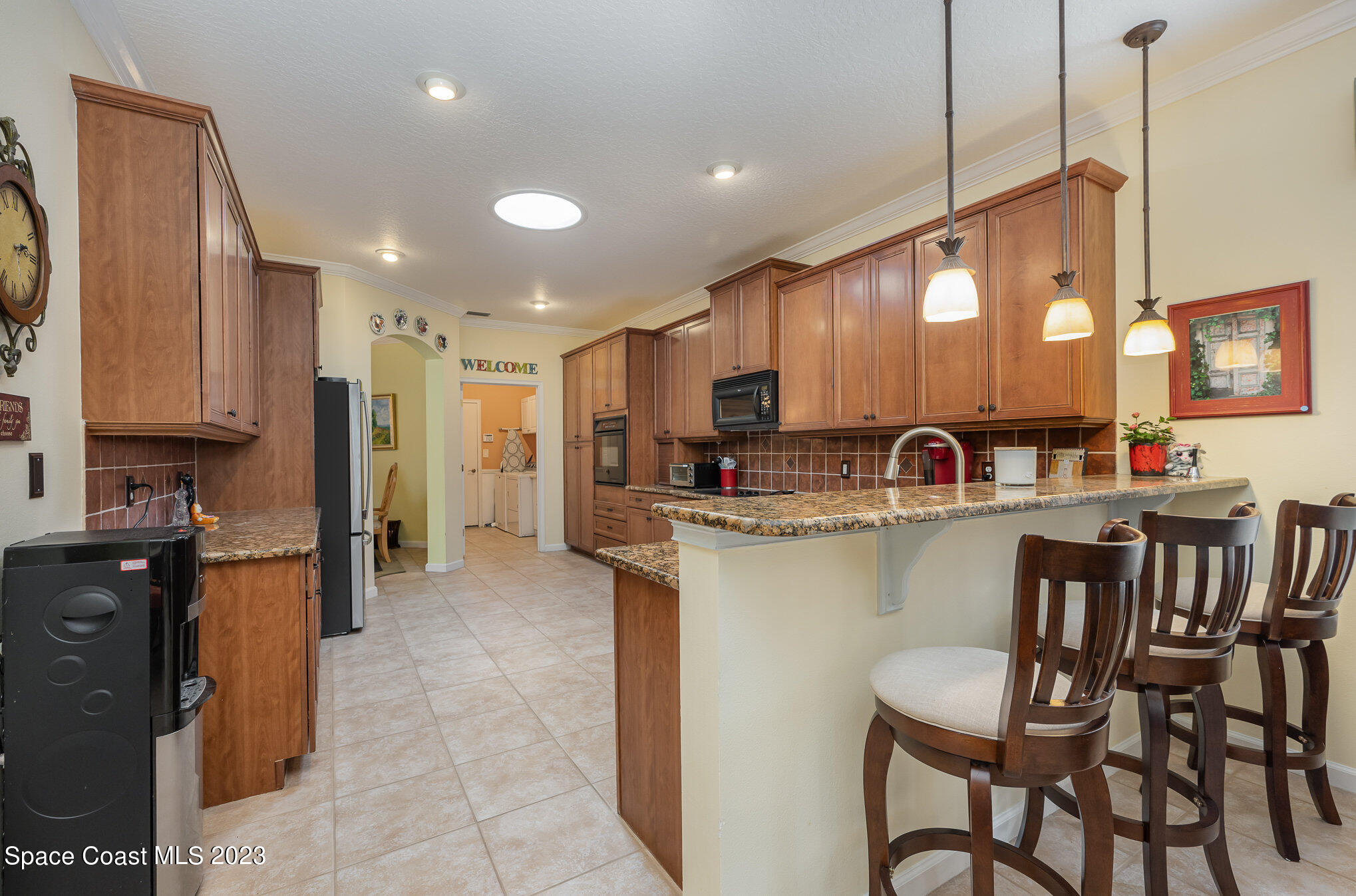6972 Premonition Drive Melbourne, FL 32940 - Photo 10 of 33 a kitchen with kitchen island granite countertop a dining table chairs refrigerator and sink