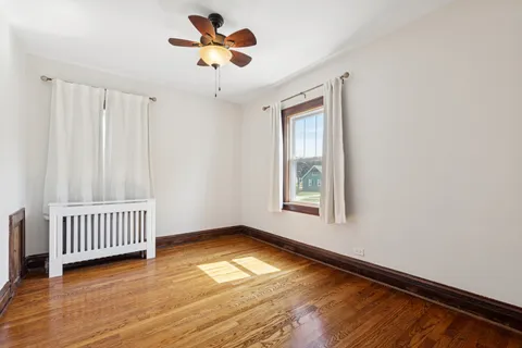 a view of an empty room with window and a chandelier fan