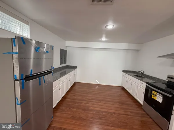 a kitchen with granite countertop a refrigerator a sink and a stove top oven