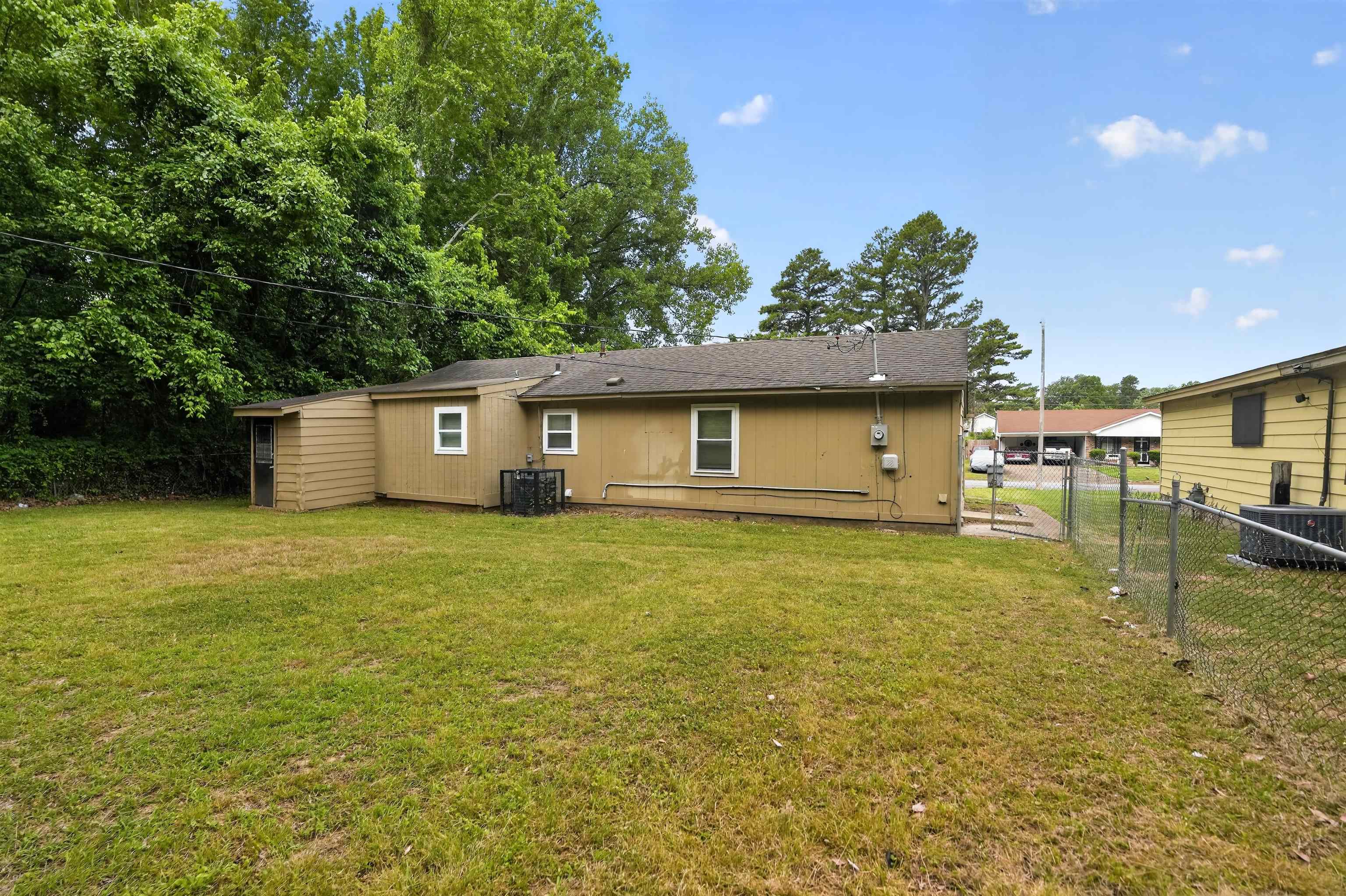 3608 Cane Ridge Drive Memphis, TN 38109 - Photo 10 of 31 Expansive grassy backyard featuring a chain-link fence, mature trees, and a detached shed