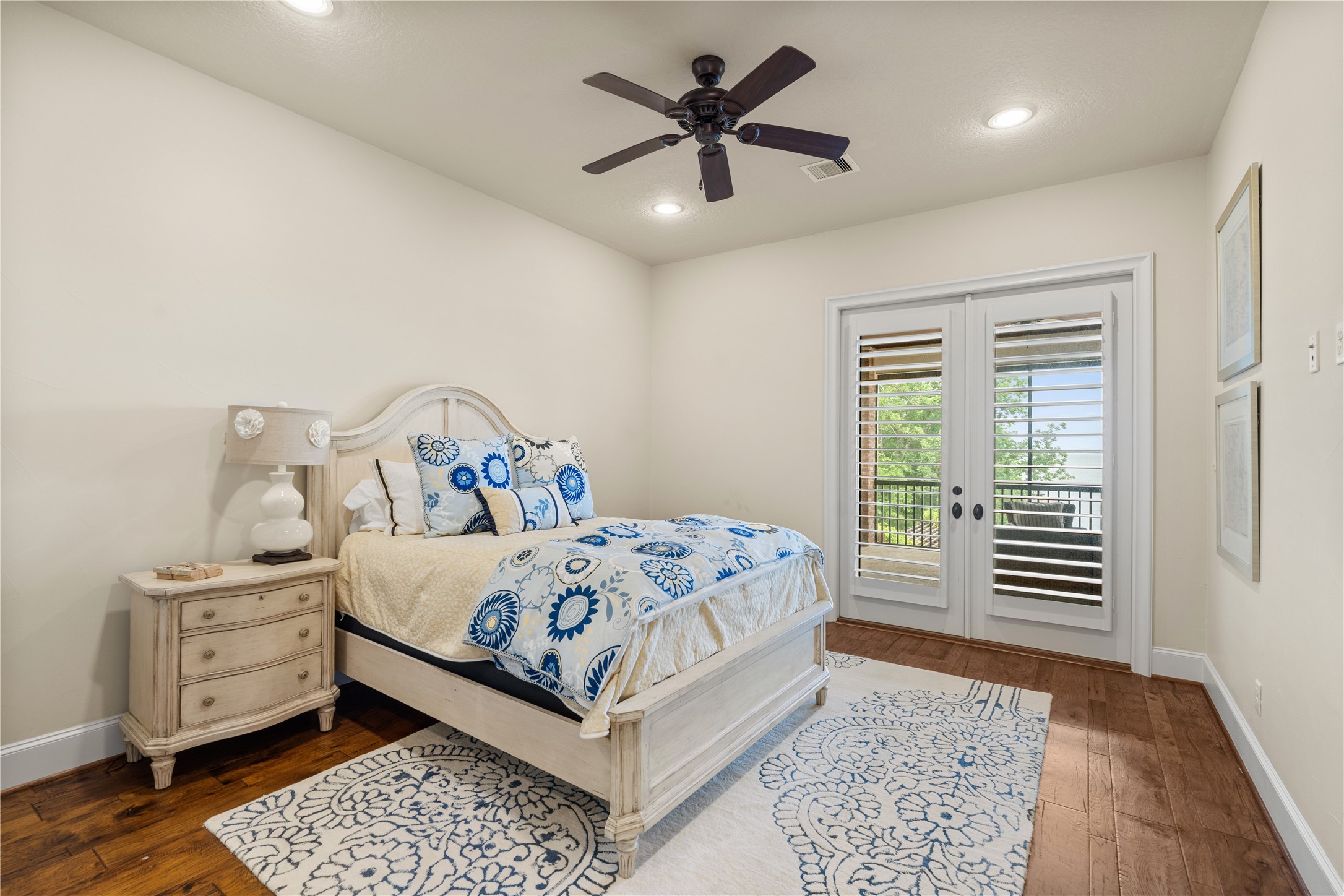 12349 Longmire Trace Conroe, TX 77304 - Photo 29 of 48 Sunlit bedroom with hardwood floors, recessed lighting, and French doors opening to a private balcony.