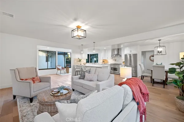 a living room with furniture kitchen view and a chandelier
