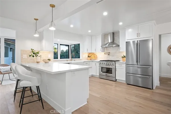 a kitchen with stainless steel appliances a refrigerator a stove a sink and a dining table with wooden floor