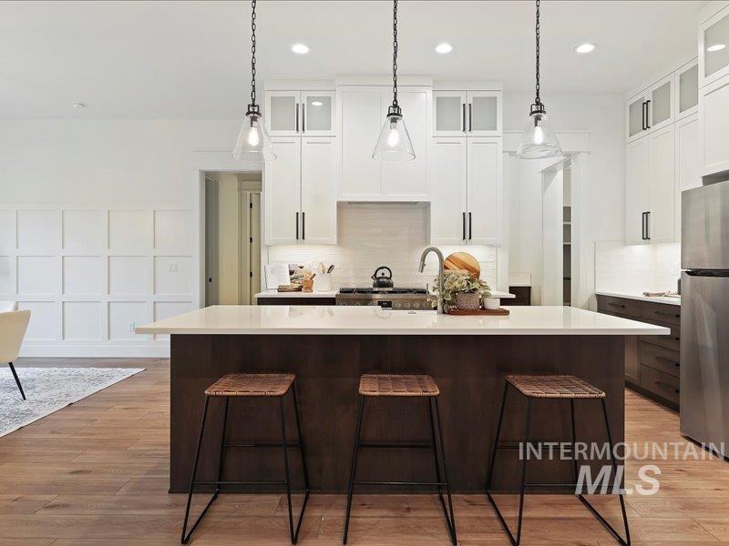3882 West Haverhill Street Eagle, ID 83616 - Photo 14 of 38 Kitchen with glass insert cabinets, white cabinets, freestanding refrigerator, dark brown cabinetry, and an island with sink