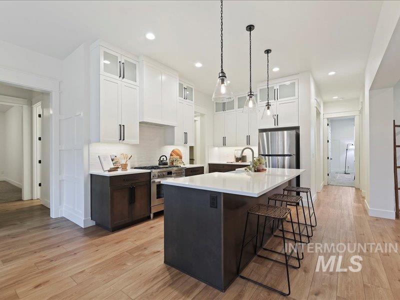 3882 West Haverhill Street Eagle, ID 83616 - Photo 16 of 38 Kitchen with glass insert cabinets, a center island with sink, white cabinets, and recessed lighting