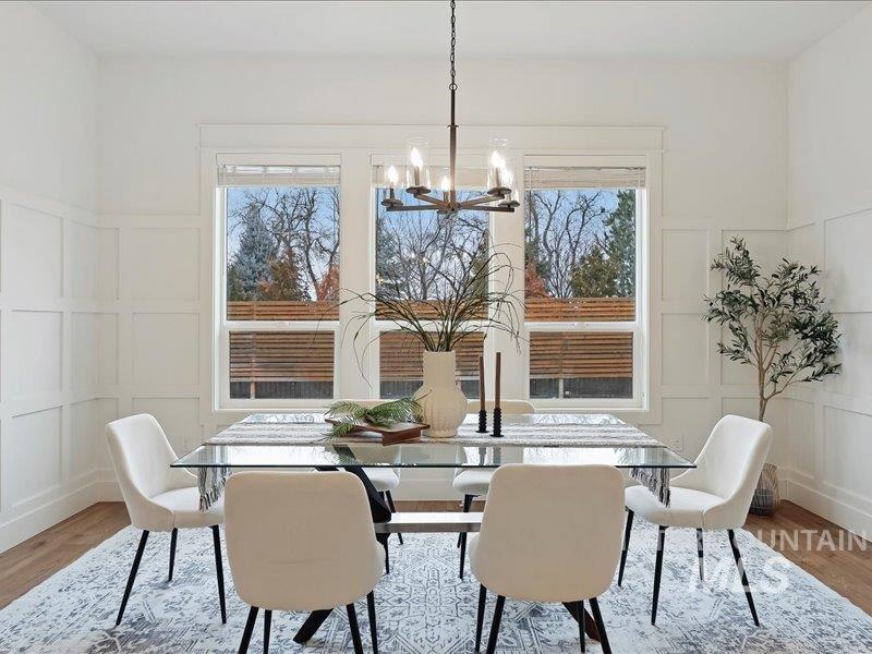 3882 West Haverhill Street Eagle, ID 83616 - Photo 20 of 38 Dining space featuring a decorative wall, wood finished floors, wainscoting, and a chandelier