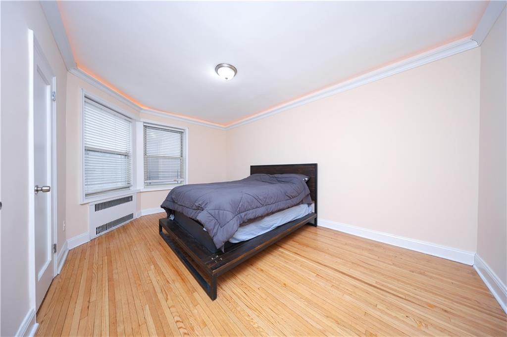 9281 Shore Road, Unit 220 Brooklyn, NY 11209 - Photo 15 of 17 a spacious bedroom with a bed and wooden floor