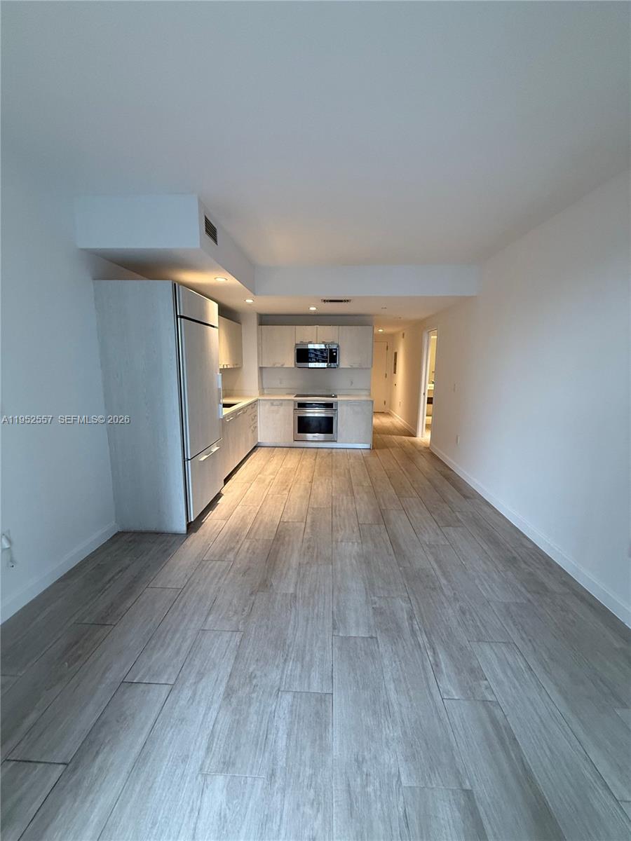 45 Southwest 9th Street, Unit 1004 Miami, FL 33130 - Photo 14 of 16 an empty room with wooden floor fireplace and windows