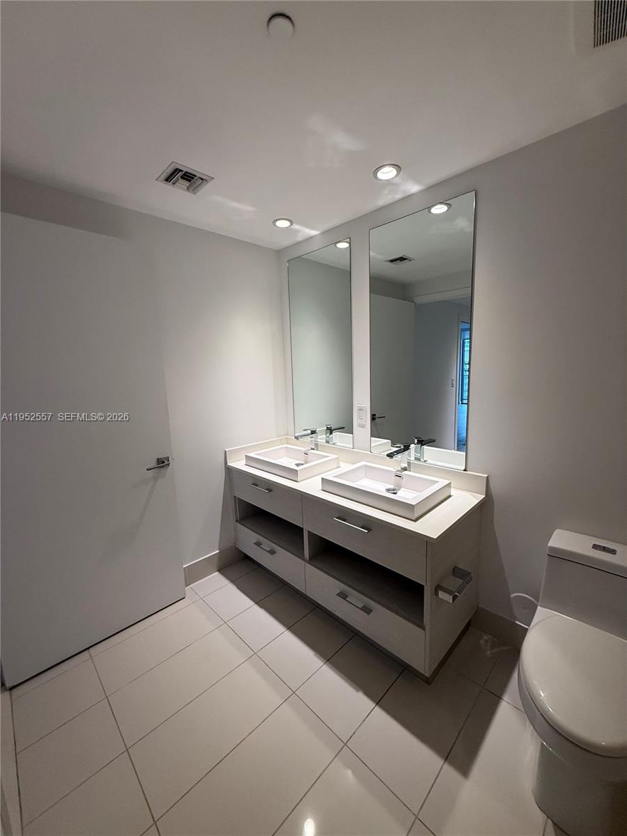 45 Southwest 9th Street, Unit 1004 Miami, FL 33130 - Photo 10 of 16 a bathroom with a sink a toilet a mirror and vanity