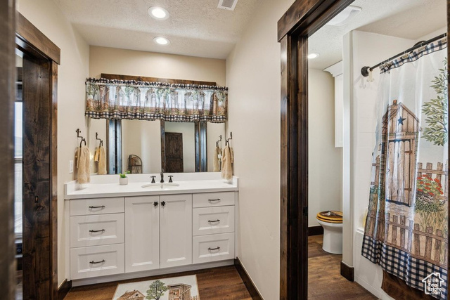 6117 North Rocky Ridge Road Peoa, UT 84061 - Photo 62 of 83 Bathroom featuring hardwood / wood-style flooring, vanity, a textured ceiling, curtained shower, and toilet