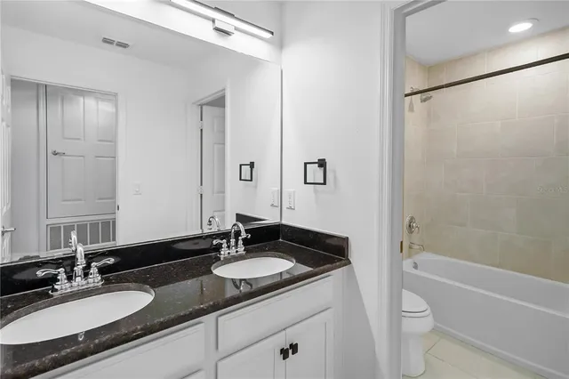 a bathroom with a granite countertop sink toilet a shower and a mirror
