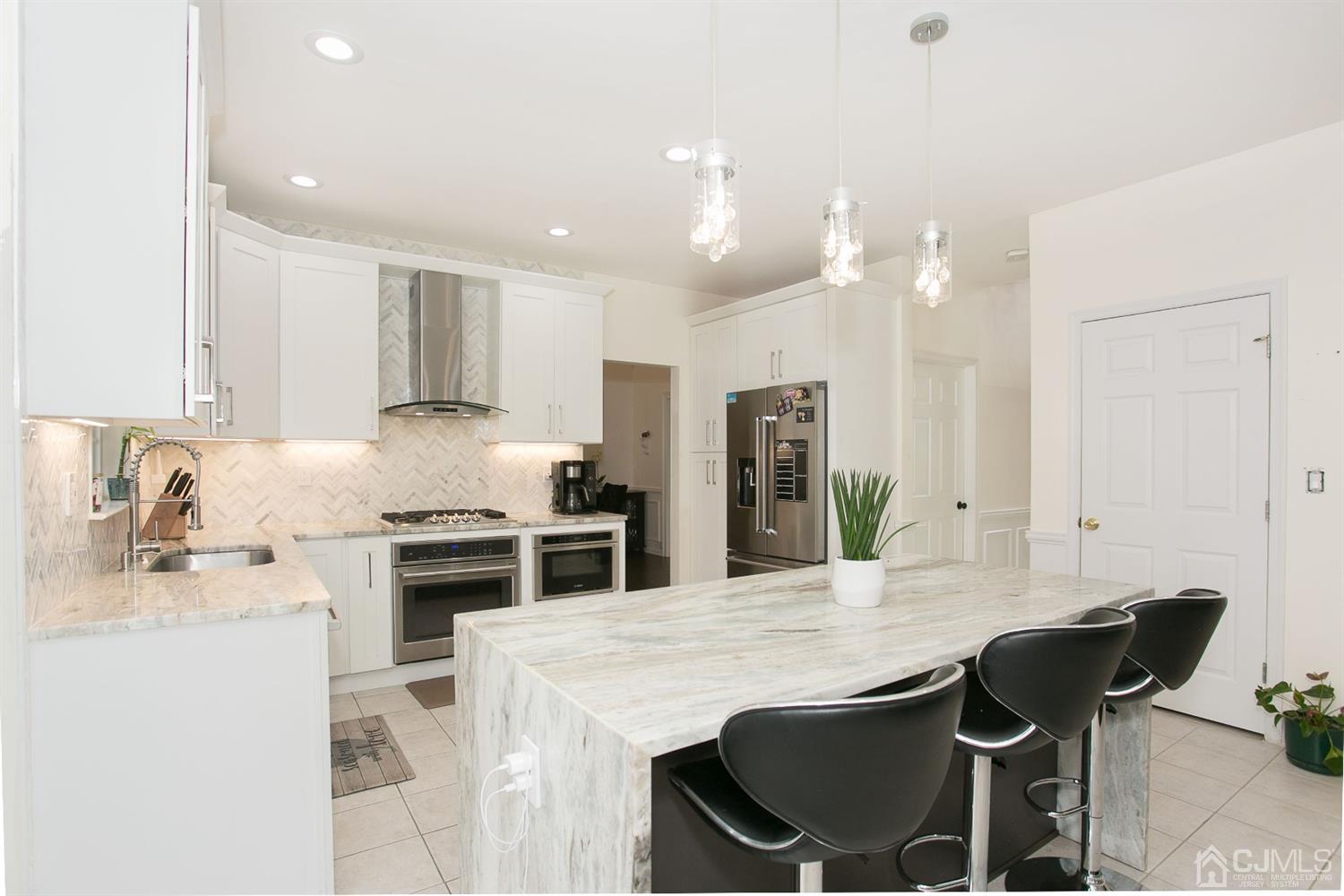12 Lenox Street Edison, NJ 08817 - Photo 16 of 33 a kitchen with stainless steel appliances kitchen island granite countertop a stove a sink a refrigerator and white cabinets with wooden floor