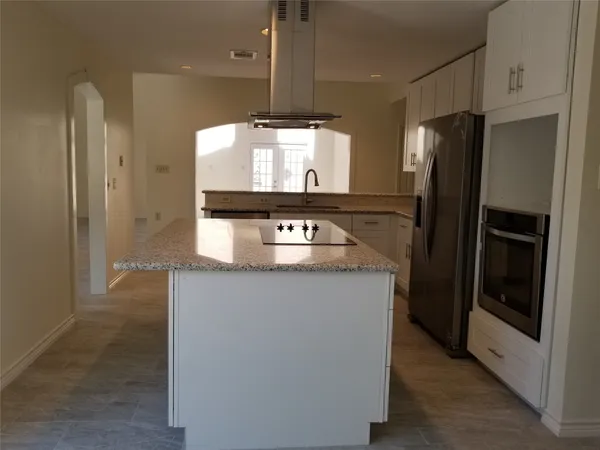 a kitchen with stainless steel appliances granite countertop a refrigerator a stove and a sink with wooden floor