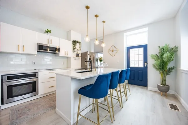 a kitchen with a sink a stove a chandelier and wooden floor