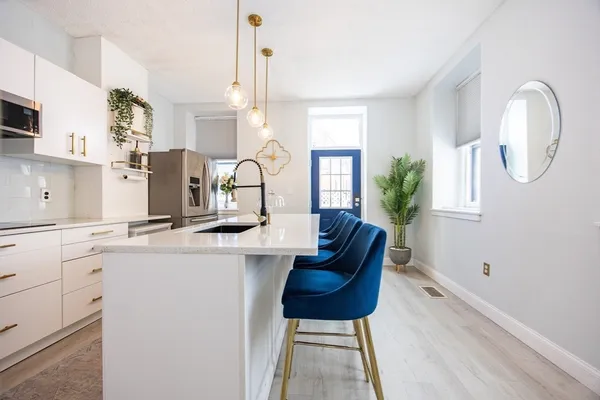 a kitchen with stainless steel appliances a stove a sink a refrigerator a center island and chairs
