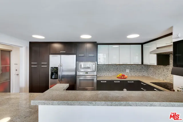a kitchen with stainless steel appliances granite countertop a refrigerator a sink a stove and a sink