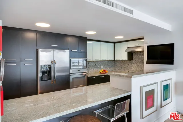 a kitchen with stainless steel appliances a refrigerator a sink a stove a microwave a counter space and cabinets