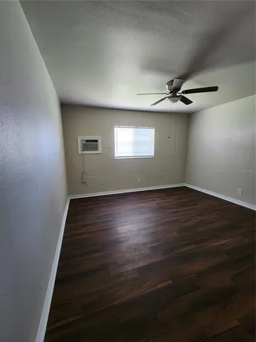 an empty room with wooden floor chandelier and windows