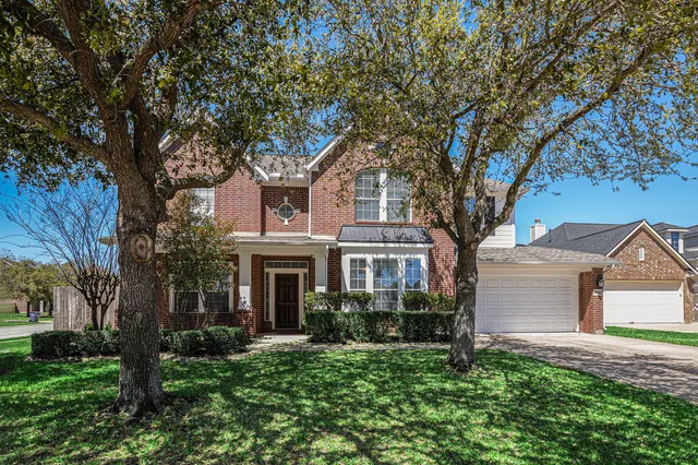 a front view of a house with a garden and trees