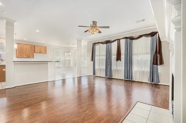 a view of an empty room with wooden floor and windows