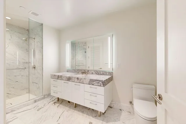 a bathroom with a granite countertop sink mirror vanity and toilet