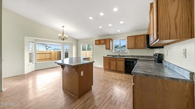 a kitchen with kitchen island granite countertop wooden floors stainless steel appliances a sink and a counter space