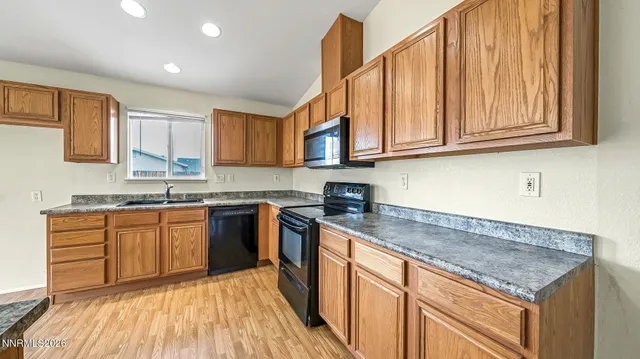 a kitchen with granite countertop a sink dishwasher stove and cabinets