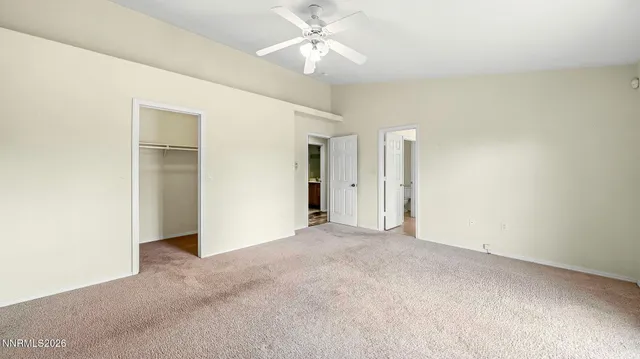 an empty room with closet and a ceiling fan