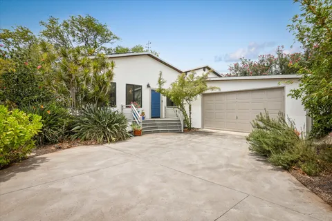 front view of a house with a yard and potted plants
