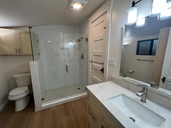 a bathroom with a sink a toilet a mirror and shower