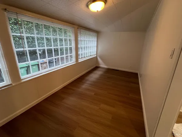 a view of an empty room with wooden floor and windows