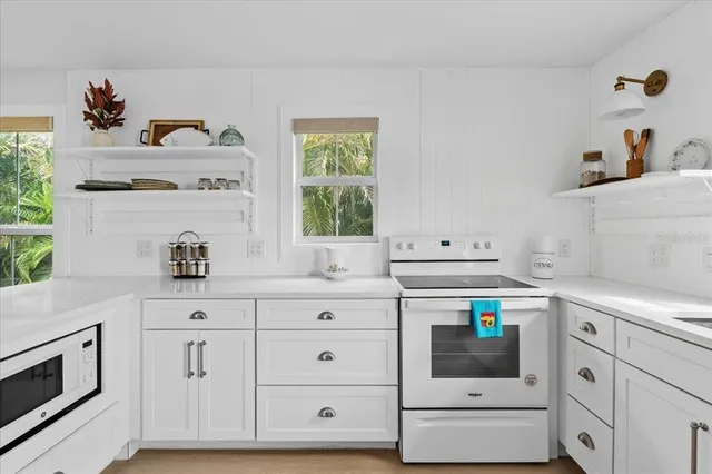 a kitchen with white cabinets and appliances