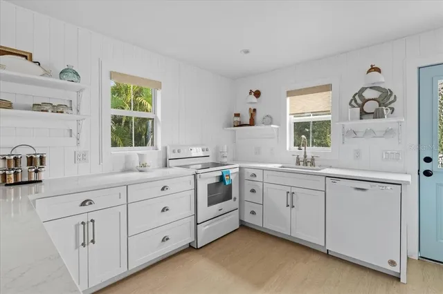 a large white kitchen with cabinets a sink a window and a refrigerator