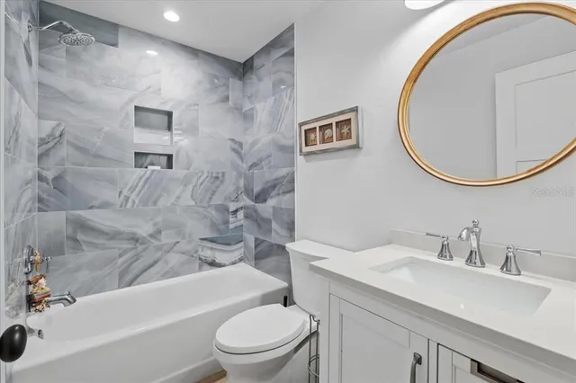 a bathroom with a toilet a sink a mirror and bathtub