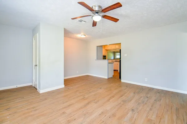 a view of empty room with wooden floor and ceiling fan