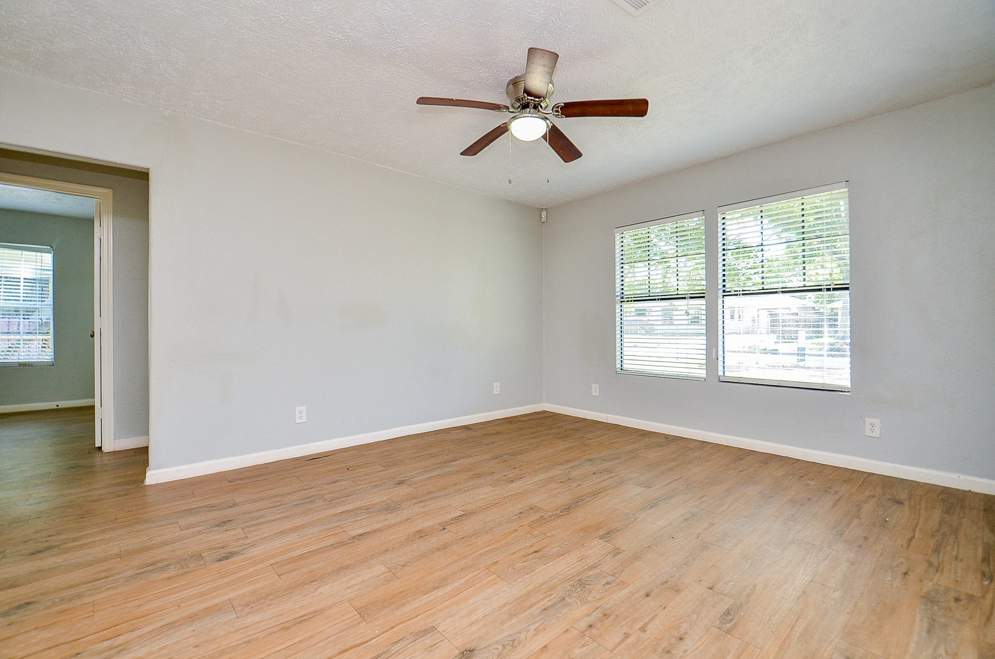 5405 Southlea Street Houston, TX 77033 - Photo 6 of 32 an empty room with wooden floor fan and windows
