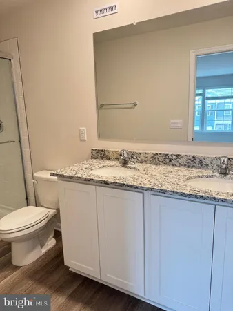 a bathroom with a granite countertop sink and a toilet