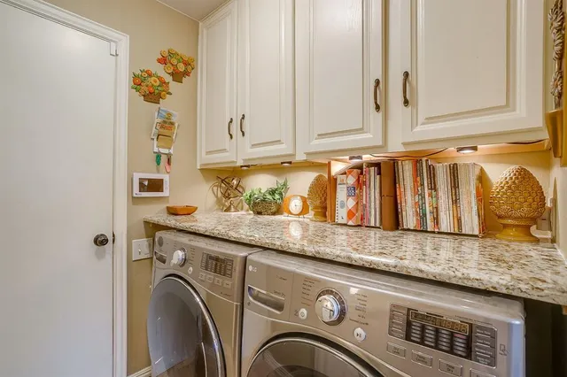 a utility room with granite countertop white cabinets and a wooden floor