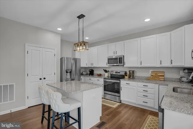 a kitchen with stainless steel appliances granite countertop a stove top oven a refrigerator a sink and dishwasher with wooden floor