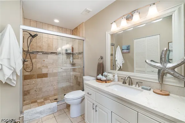 a bathroom with a granite countertop sink a toilet a mirror and shower