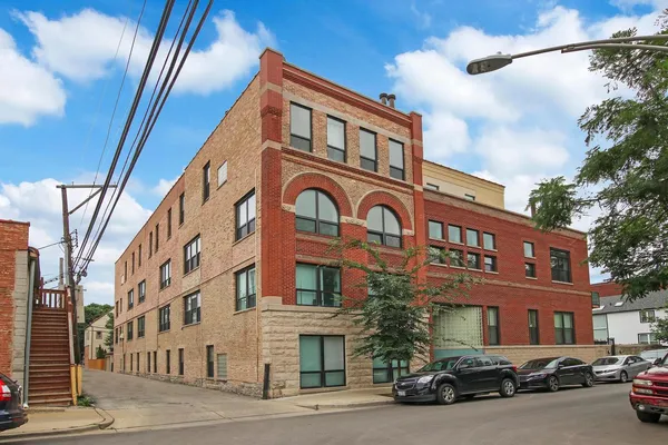 a front view of a building with lot of cars and trees