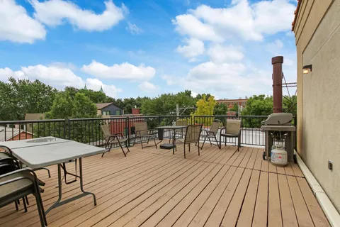 a view of a roof deck with table and chairs with wooden floor and fence