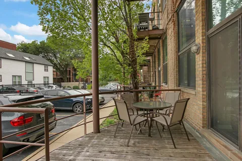 a view of a patio with table and chairs and barbeque with wooden floor and fence
