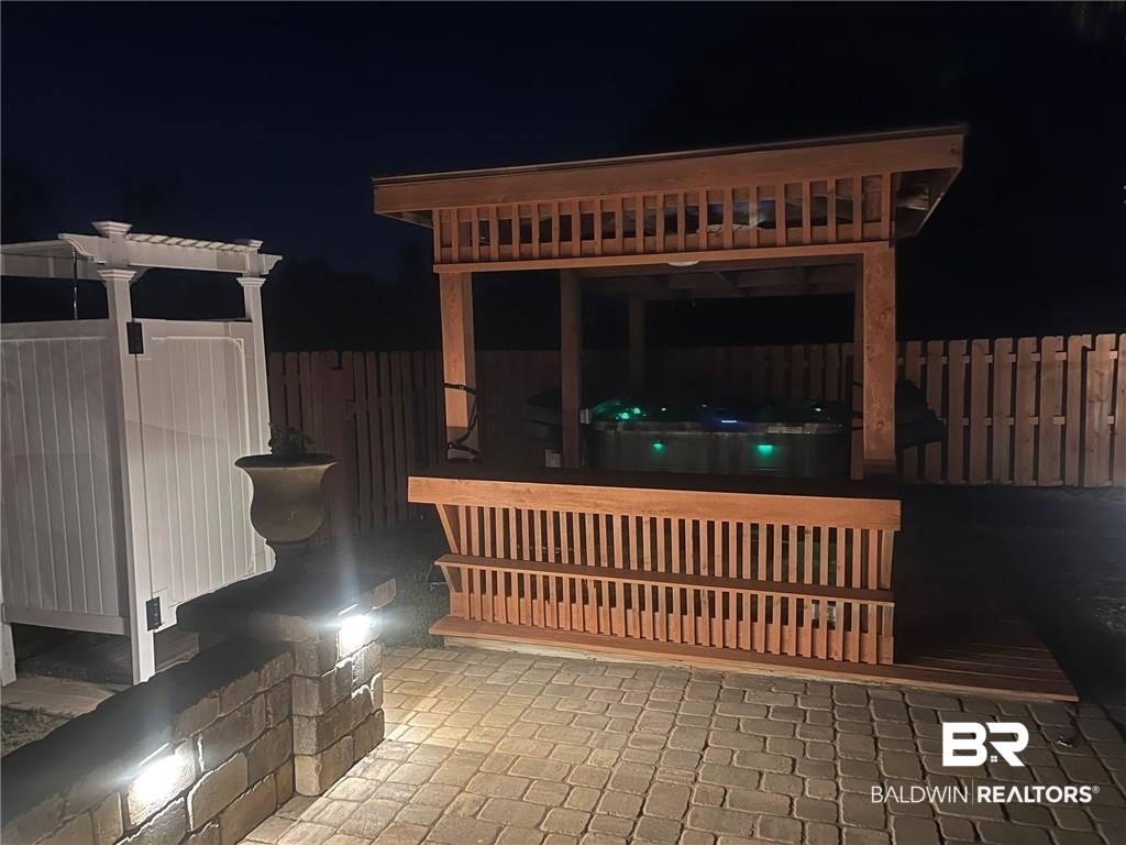 16311 Old Brady Road Bay Minette, AL 36507 - Photo 35 of 38 Covered hot tub area with a slatted wood enclosure, paver patio, wood privacy fence, and a white pergola structure